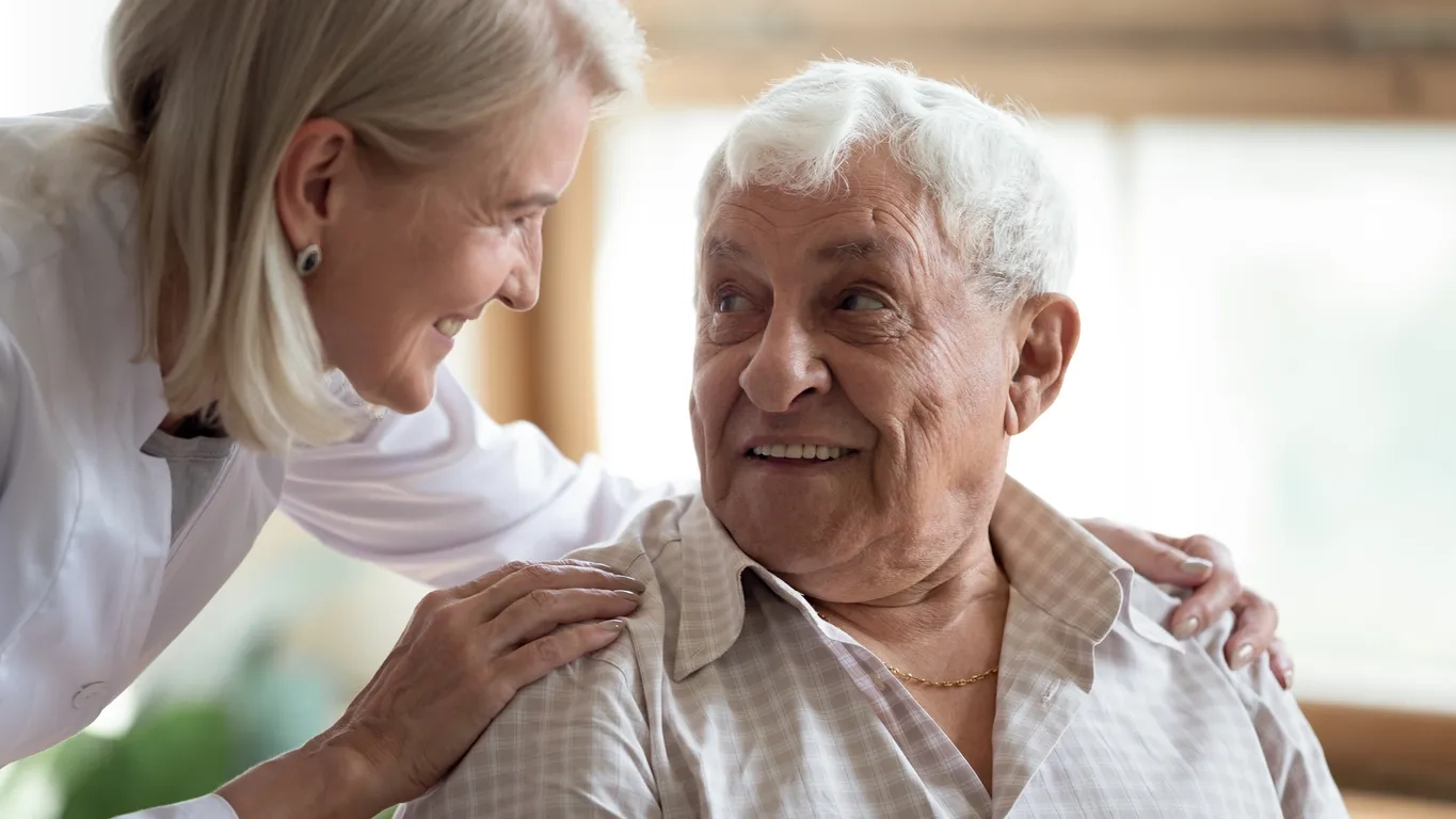 Elderly father and middle aged daughter smiling at each other