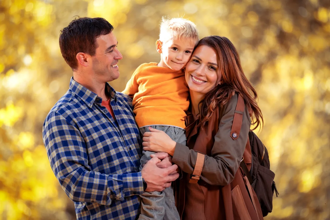 Happy family with one child walking in beautiful autumn park
