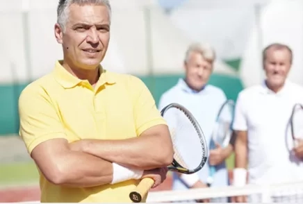 older man holding tennis racket