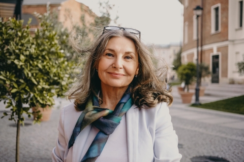 Woman in her 50's looking stood outside smiling