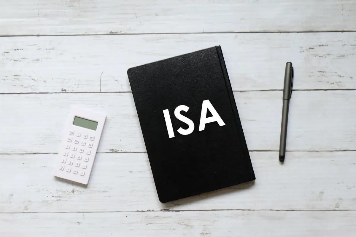 Top view of calculator pen and notebook written ISA (individual saving account) on white wooden background