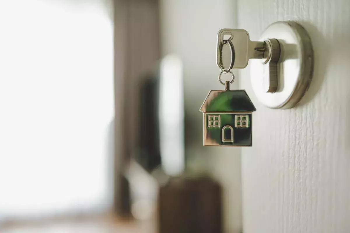 Open door and door handle with a key and a keychain shaped house