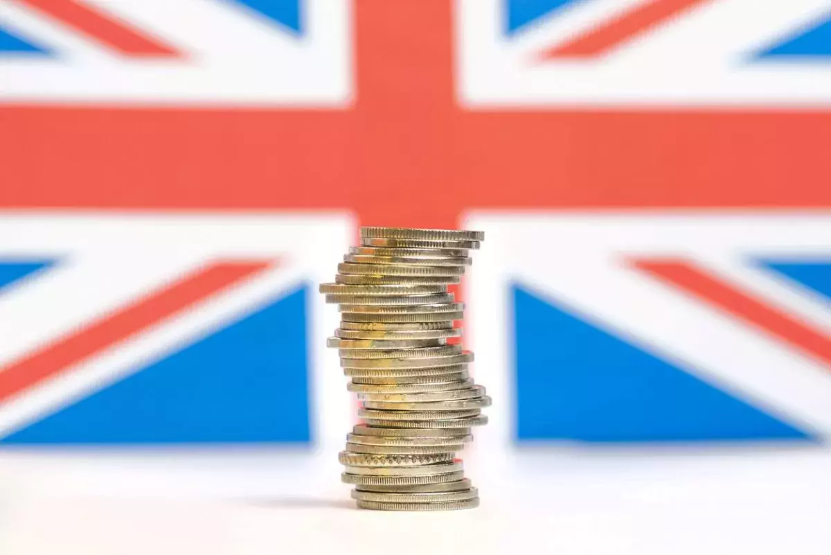 Coins stacked on each other in different positions with UK flag background