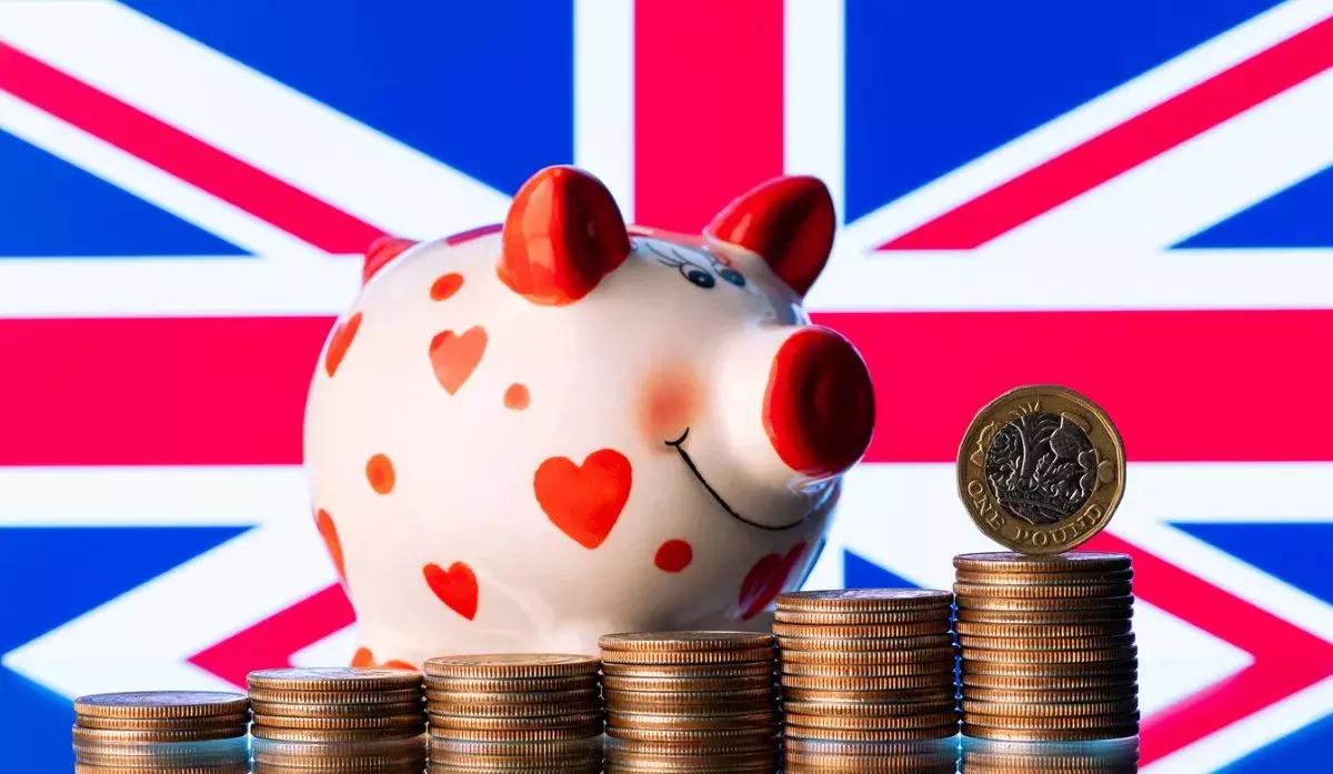1 British pound coin and piggy bank with the UK flag in the background