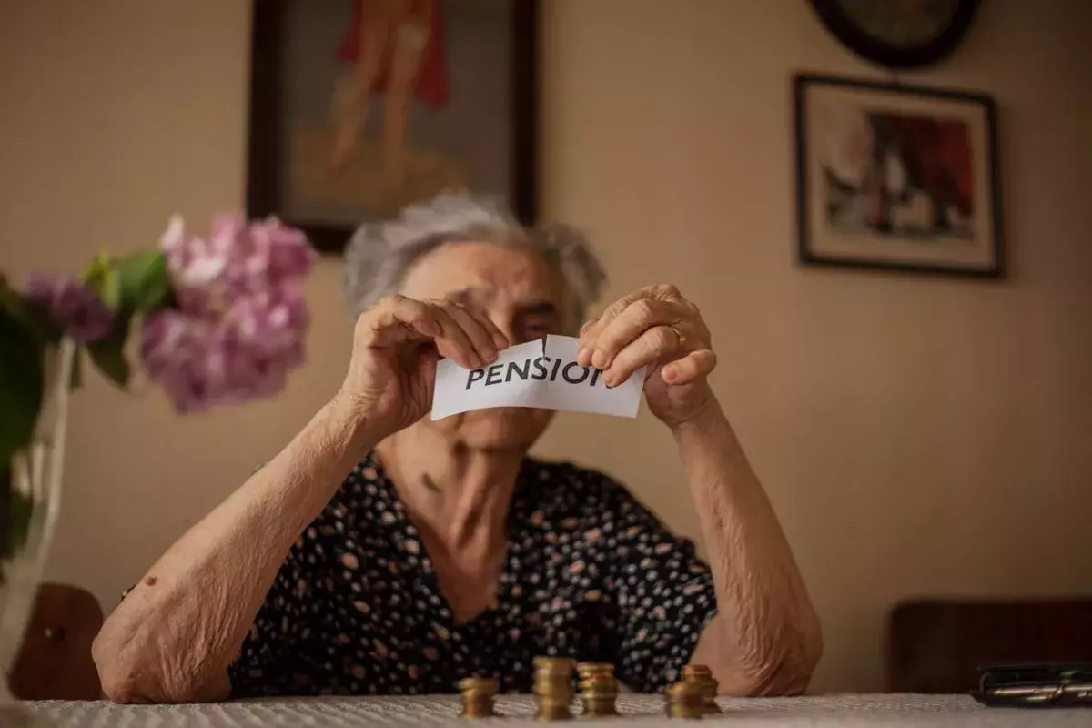 Portrait of female pensioner tearing paper with the word pension
