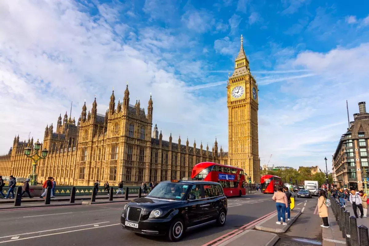 Double-decker buses and black cabs on Westminster bridge with Big Ben and Houses of Parliament at background