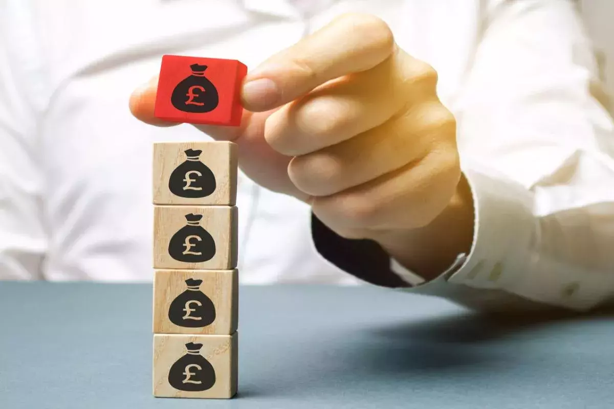 Businessman builds wooden blocks with the pound sterling symbol