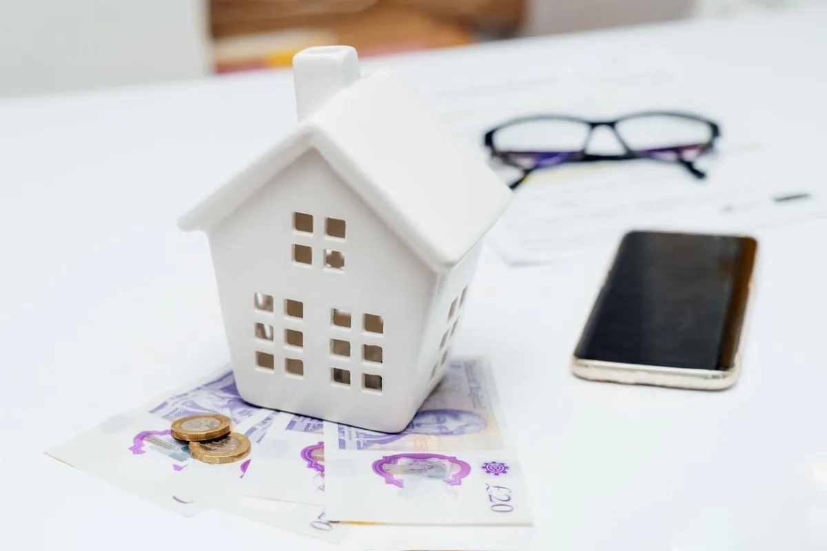 House model with British currency, bill documents and phone on table