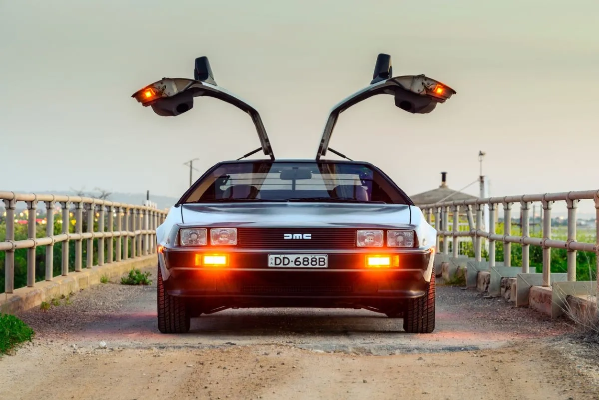 DeLorean DMC-12 car with opened gullwing doors parked on the bridge at dusk