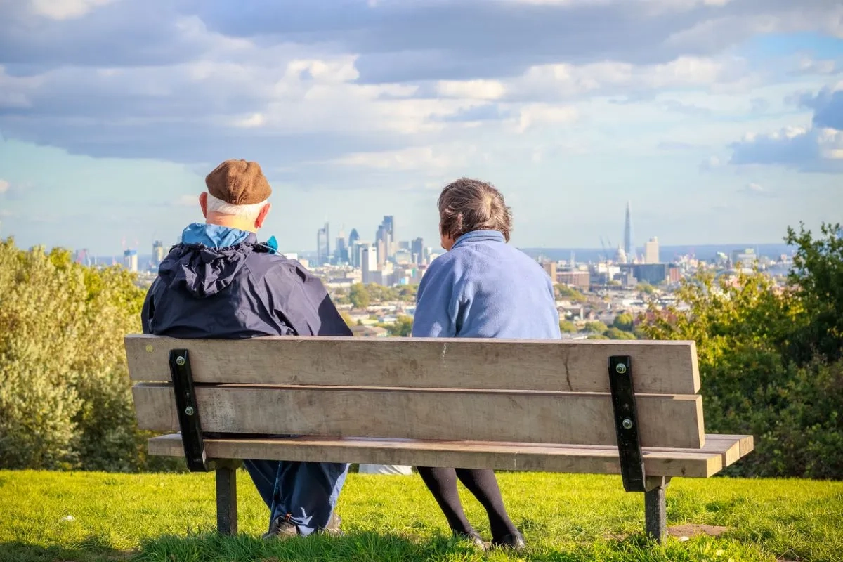 Back view of senior couple looking over London city skyline from Hampstead Heath