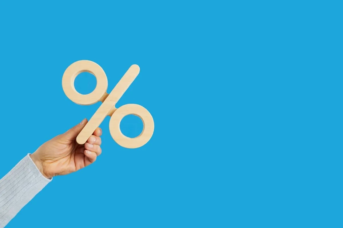 Business woman holding percentage symbol in her hand on blue background
