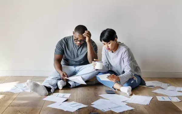 couple seated in the floor looking a few papers