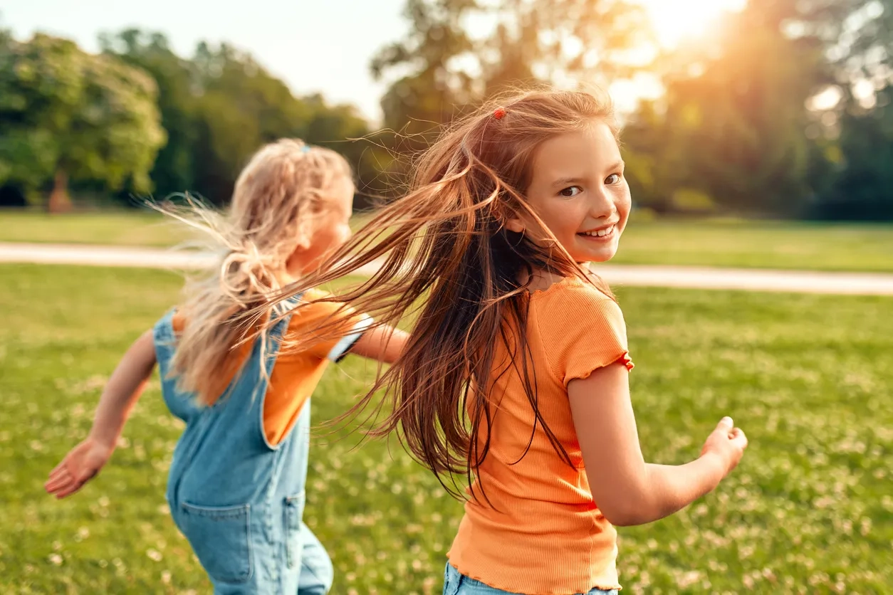 two girls running in a park in the evening sun