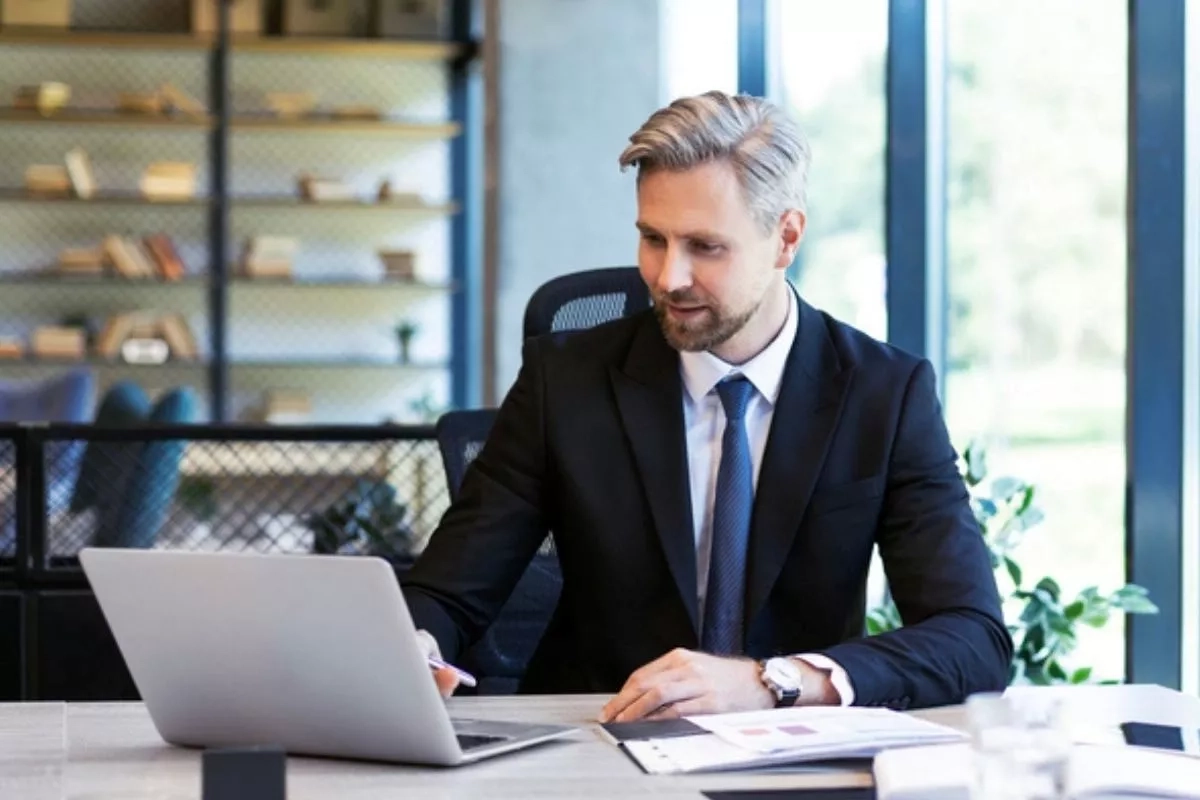 A man at a desk looking at a laptop