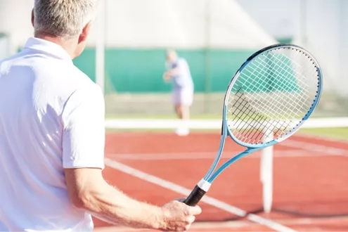 older man holding tennis racket