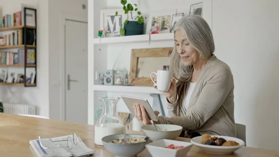 Middle aged woman on video call drinking from a mug