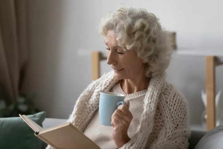 A woman reading and drinking a cup of tea