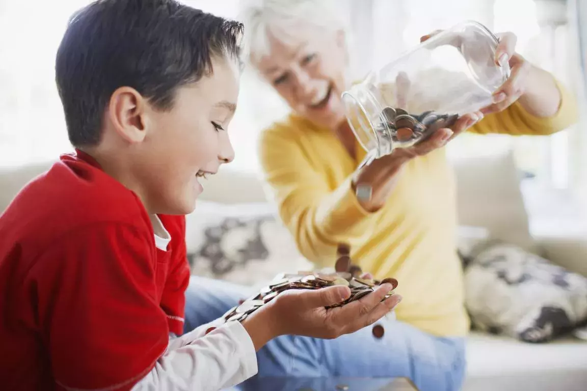 Grandmother pouring money from jar into grandson's hands