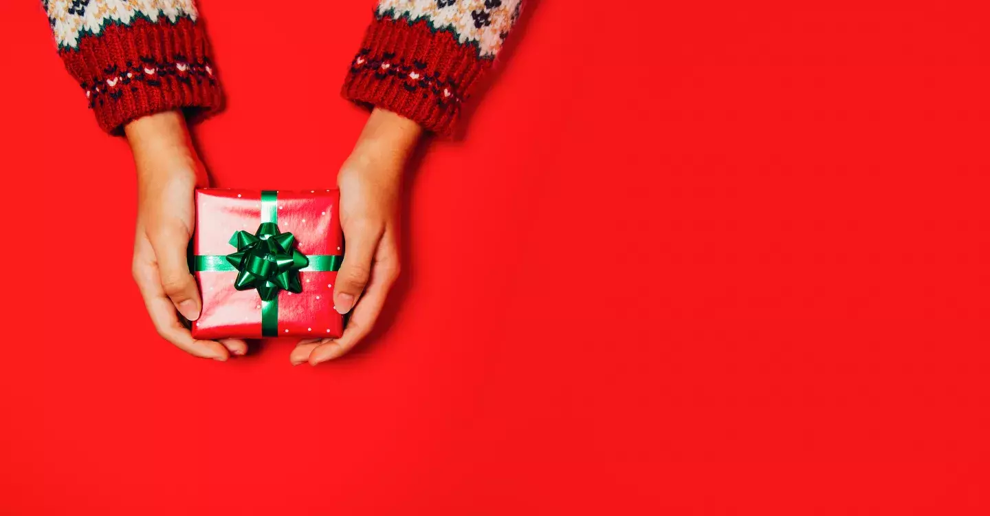 Red image with hands holding out a present