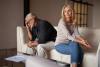 Senior man and woman sitting on a couch, upset with with each other.