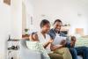 couple sitting on sofa reading information on a tablet