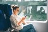 Young woman sitting on a train looking at phone and thinking about the benefits of an ISA