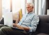 Senior man, in sofa using laptop