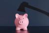 Shadow of an axe above a pink piggy bank on dark blue background