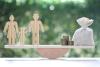 Model family and money bag on wood scale seesaw on natural green background