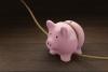 Pink piggy bank is tightened by a rope on wooden table