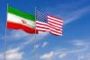USA and Iran flags over blue sky background
