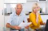 Worried mature couple with documents discussing at home