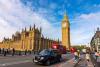 Double-decker buses and black cabs on Westminster bridge with Big Ben and Houses of Parliament at background
