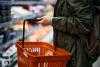 Close-up of woman shopping groceries in supermarket with a red basket
