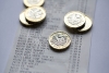Five UK one pound coins placed on a till receipt.