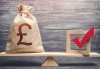 Red vote tick and a British pound sterling money bag on a wood scale