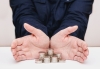 Woman palms are open, protecting money coins are stacked in stacks