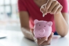 Young women put money coin in piggybank