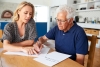 Woman helping senior man to complete paperwork