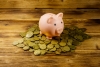 Pink piggy bank on a heap of coins on wooden background