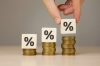 Businessman makes growing financial chart from wooden cubes and stacks of coins.