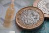 a pound coin on a five pound note showing a symbol of the big ben clock tower.
